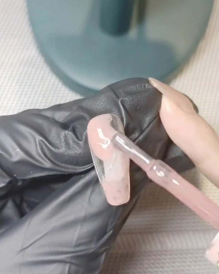 Un tip de uña reposando dentro de una lámpara UV, a mitad del proceso de curado.