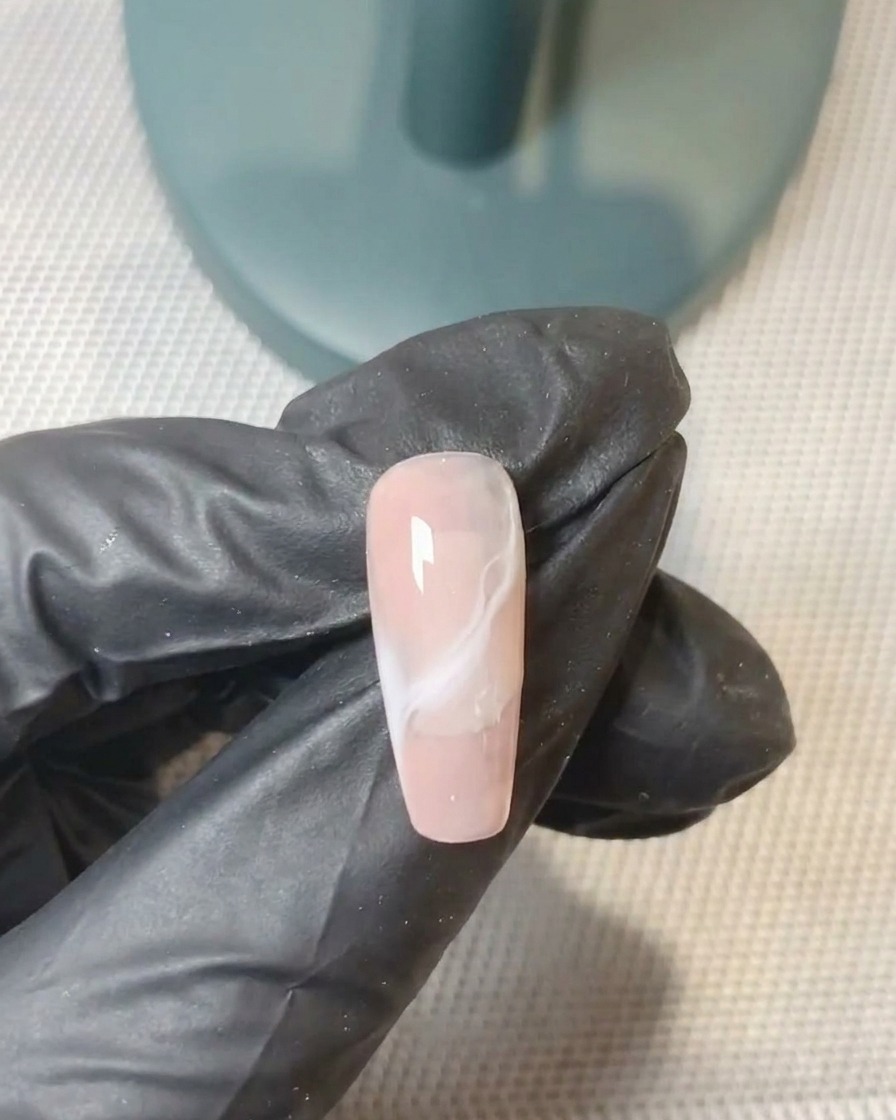 Un pincel de gel perfeccionando la mezcla de la segunda capa de gel en la uña.