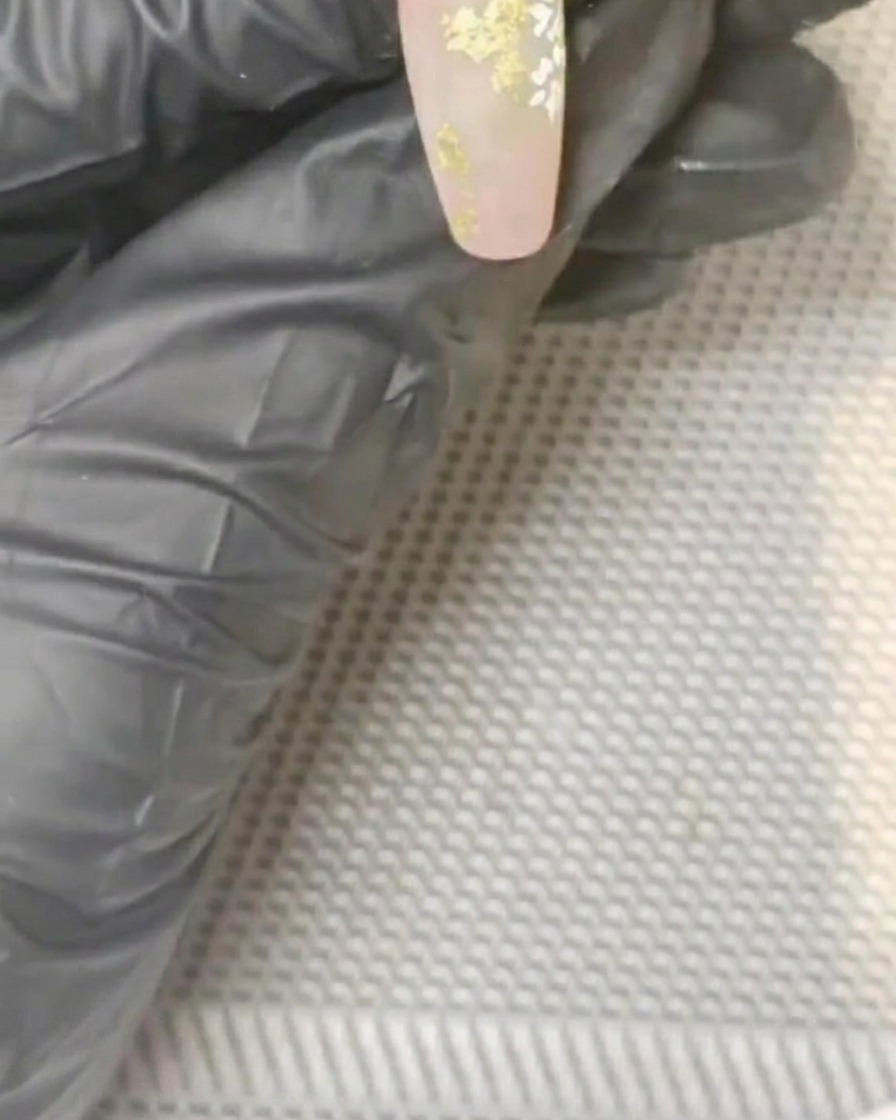 Un pincel pequeño aplicando gel amarillo en el centro de una margarita blanca pintada.
