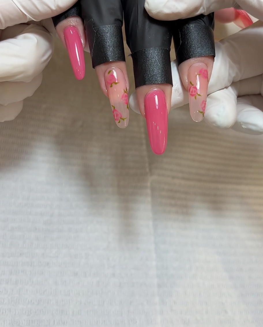 Primer plano de un pincel aplicando gel rojo más profundo en el centro de la segunda rosa sobre la uña.