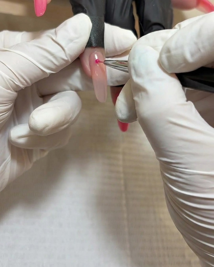 Primer plano del diseño terminado de uñas con rosas bajo la lámpara de curado.