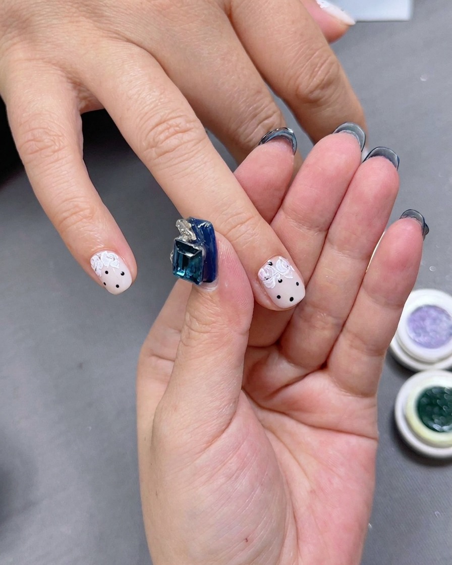 Un artista de uñas aplicando pequeños acentos de gel verde alrededor de los pétalos de la rosa.