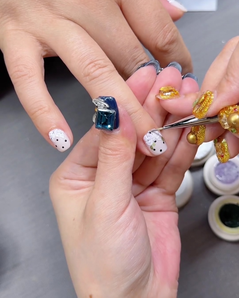 Primer plano de una mano con uñas pintadas con motivos florales descansando dentro de una lámpara LED profesional.