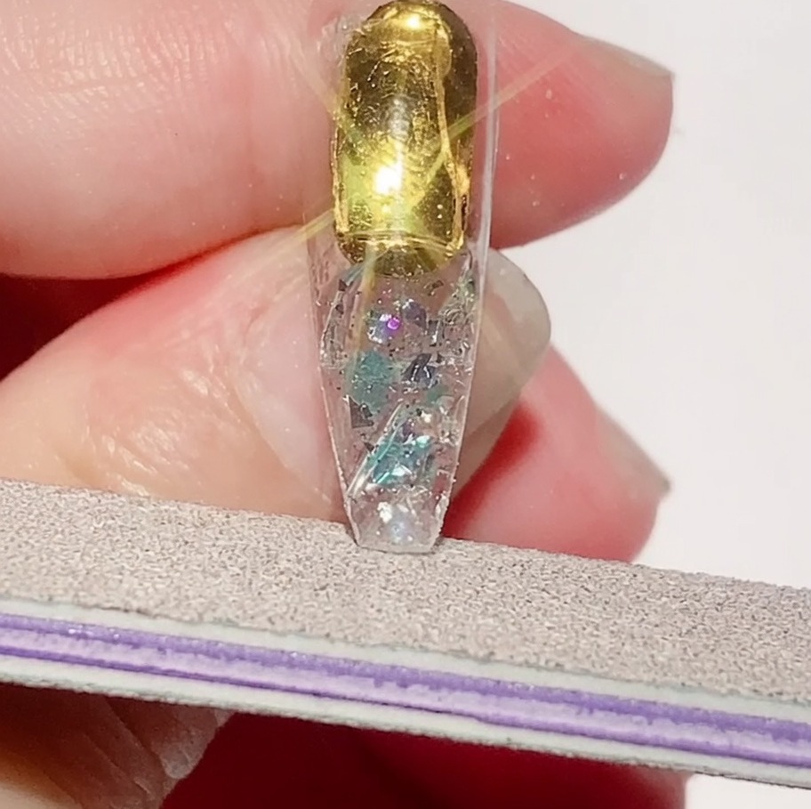 Una lima de uñas refinando los bordes de un tip texturizado para asegurar un perímetro liso.