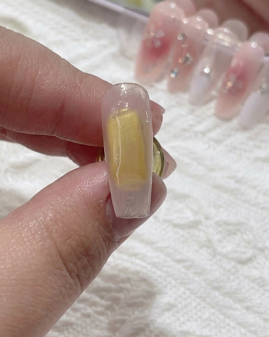 Un pincel aplicando blooming gel transparente sobre la superficie de la uña.