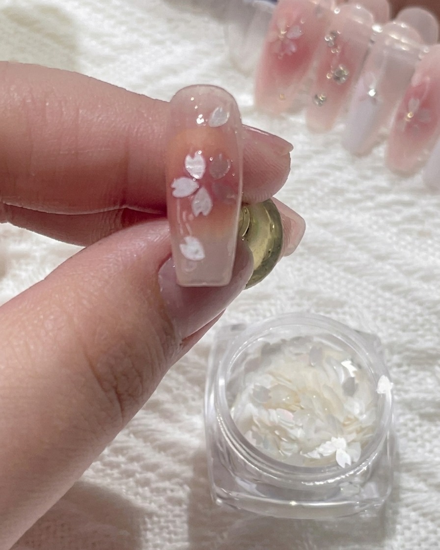 Una herramienta de precisión aplicando una pequeña gota de pegamento transparente al centro de un diseño de arte floral.