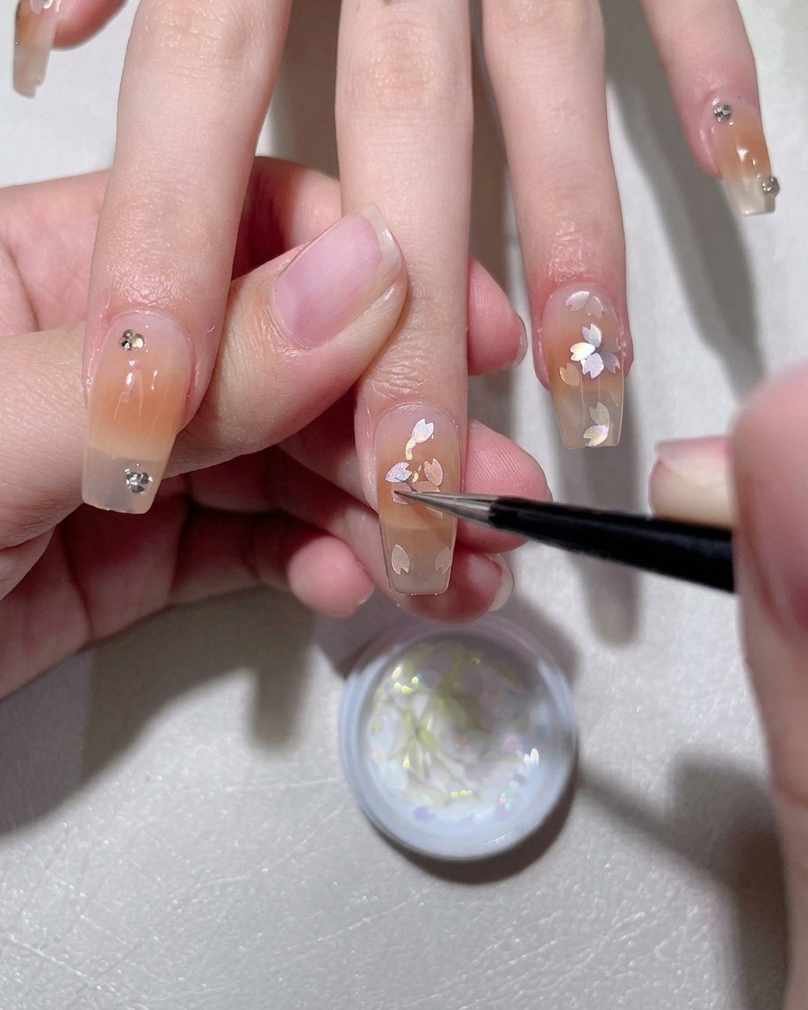 Un pincel aplicando una capa base de gel blanco lechoso sobre una uña natural.