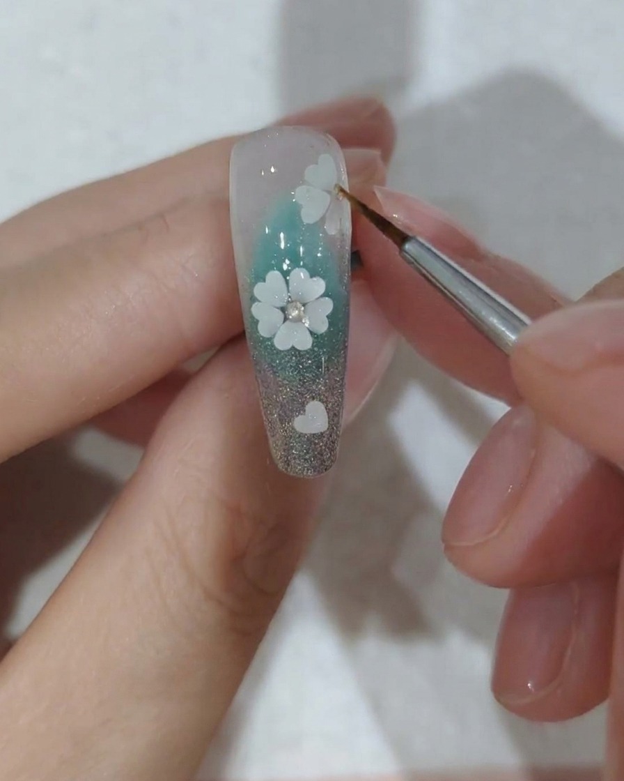 Primer plano de una uña decorada con cristales siendo colocada bajo una lámpara de uñas UV profesional para curar.