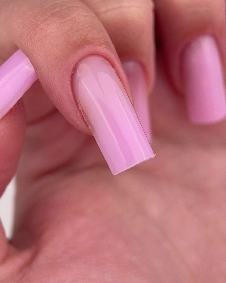 Primer plano de un dedo siendo limpiado con una almohadilla sin pelusa, revelando el acabado brillante del gel rosa.