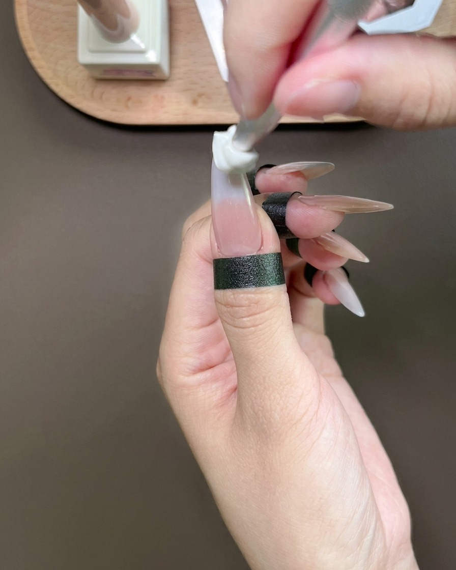 Una esponja aplicando gel azul en la punta de un pulgar para crear un degradado.