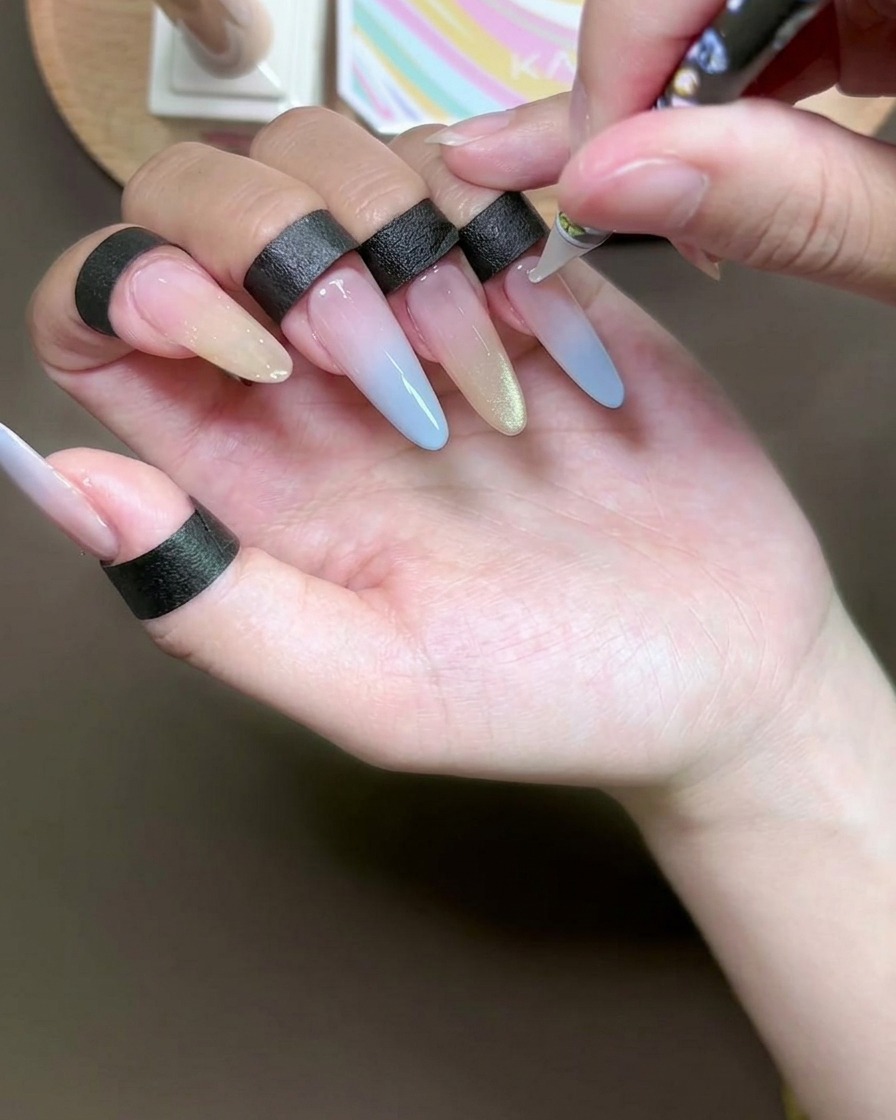 Primer plano de un punzón aplicando pequeños puntos de adhesivo transparente en una uña esmaltada con gel.