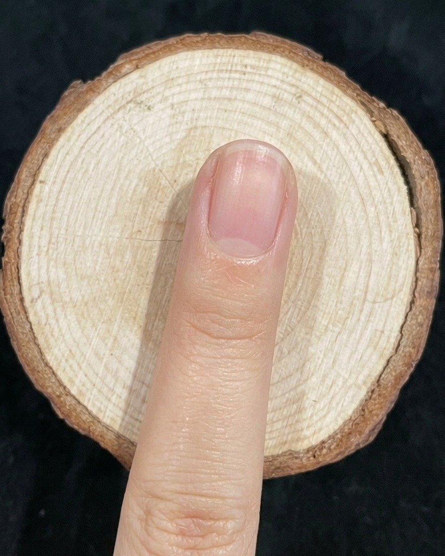 Un pincel de uñas difuminando suavemente la unión entre el esmalte verde y azul en una uña.