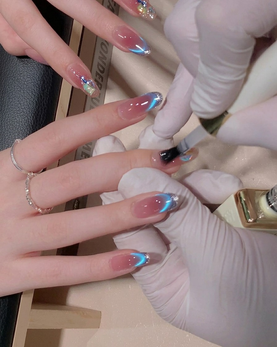 Un pincel aplicando una capa de top coat brillante sobre una uña decorada, haciendo que la superficie se vea húmeda y resplandeciente.