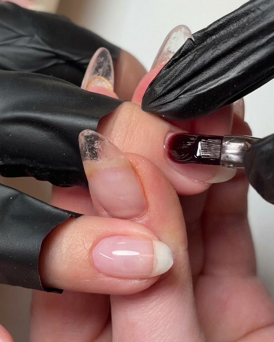 Un pincel añadiendo una pequeña perla de gel constructor a la uña para definir el ápice.