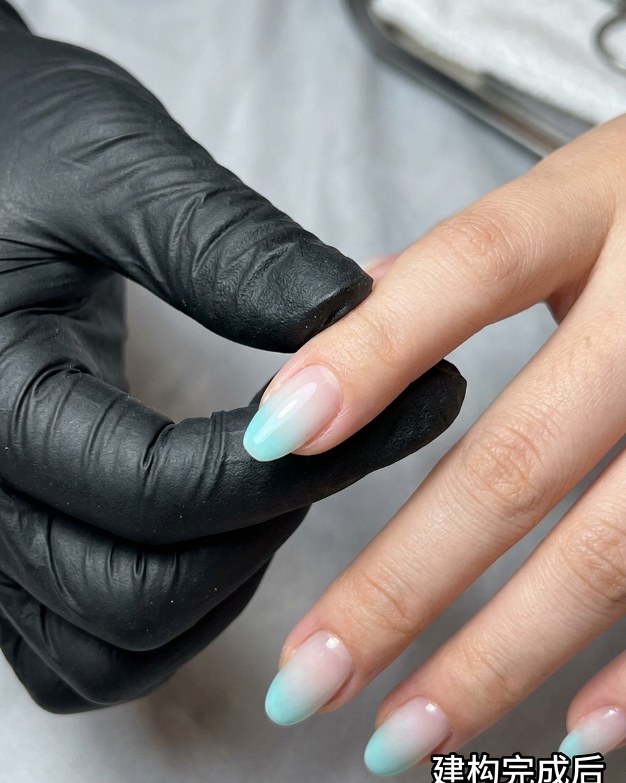 Una esponja de maquillaje aplicando esmalte de gel azul y beige sobre una uña para crear un efecto ombré.