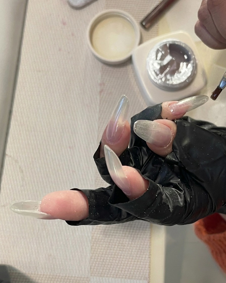 Una mano con uñas largas dentro de una lámpara UV/LED con luz de curado.