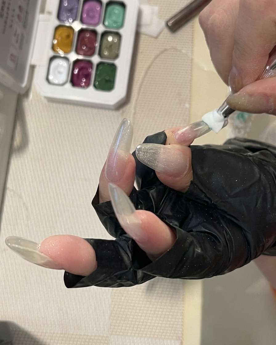 Pincel difuminando gel color verde menta en la superficie de una uña estructurada.