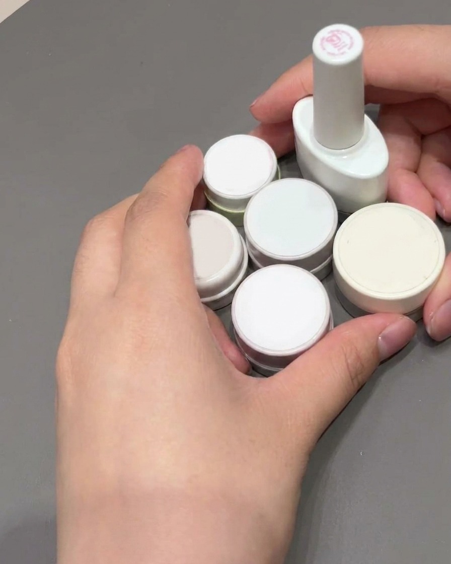 Un pincel cuadrado de uñas siendo utilizado para alisar y rellenar el gel rosa en una punta francesa.
