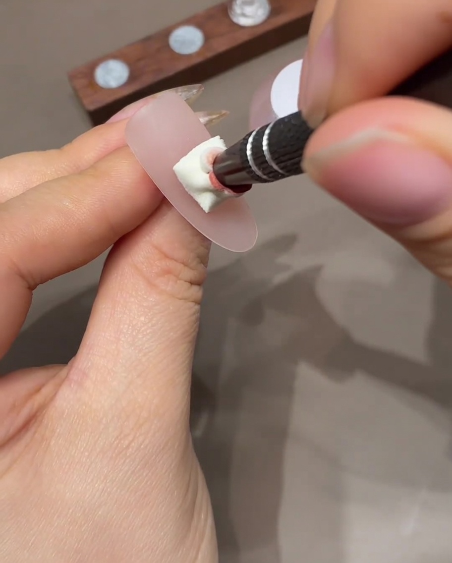 Una uña con efecto ombré curándose dentro de una lámpara profesional de uñas UV.