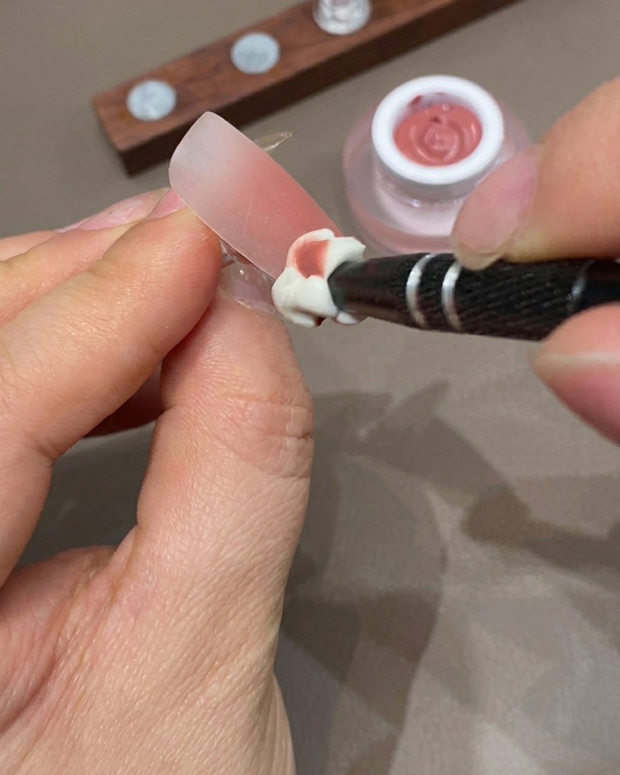 Una mano descansando dentro de una lámpara UV para curar el diseño de uñas ombré.