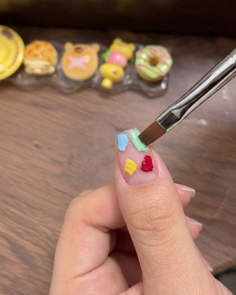 Una esponja cosmética blanca utilizada para dar ligeros toques y difuminar los cuatro cuadrados de gel colorido logrando una suave transición ombré.