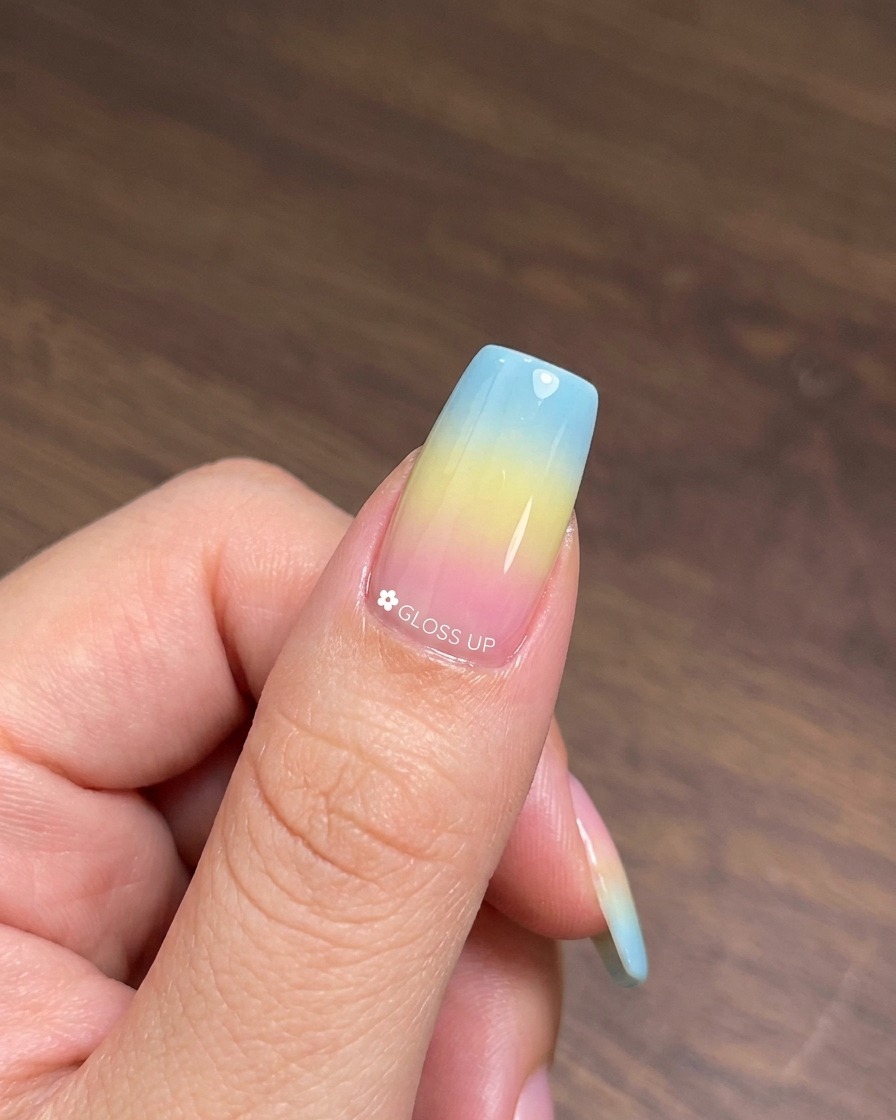 Un pincel aplicando una capa de esmalte en gel ojo de gato número 25 sobre la base curada de degradado colorido.