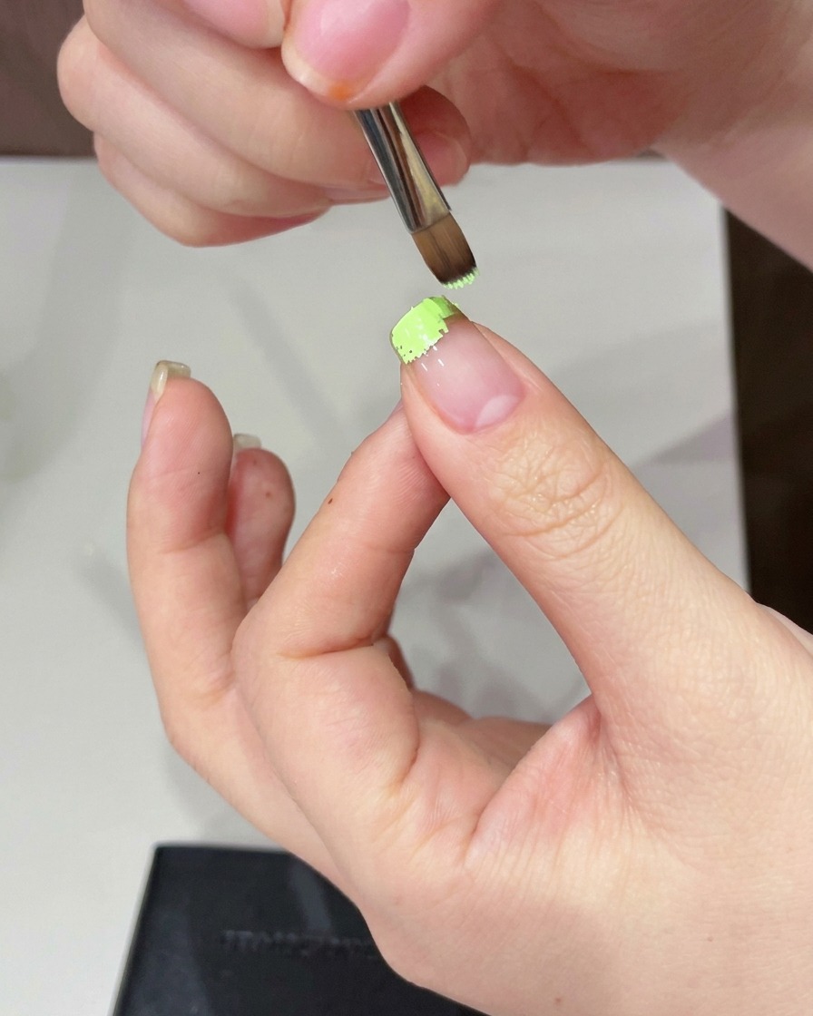 Una esponja dando pequeños toques para suavizar el gel verde en la punta de la uña.