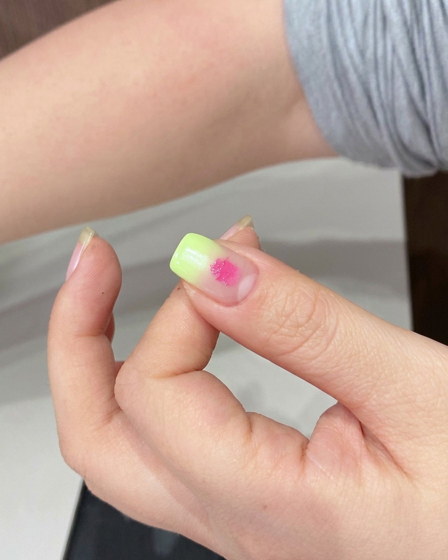 Una esponja difuminando el punto de gel rosa sobre la superficie de la uña.