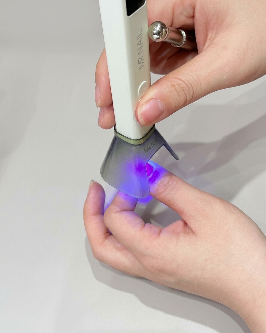 Una pequeña esponja de maquillaje aplicando esmalte de gel verde en la punta de la uña para intensificar el color.