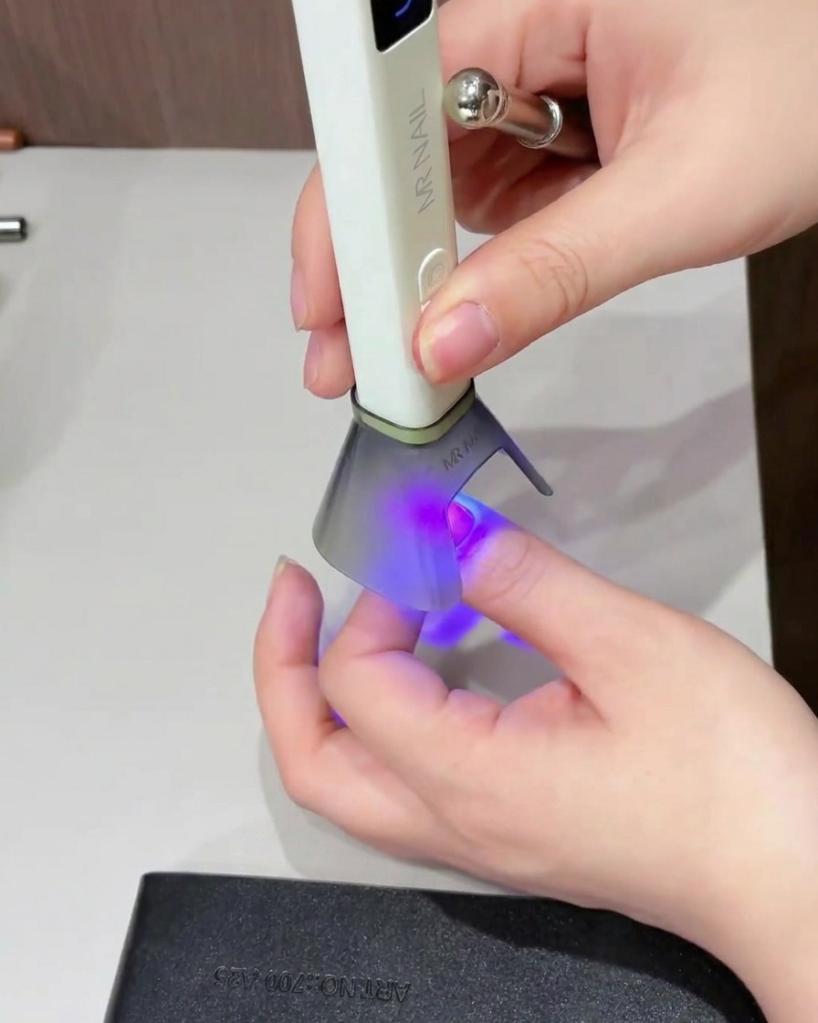 Un pincel aplicando un top coat brillante sobre toda la superficie de la uña.