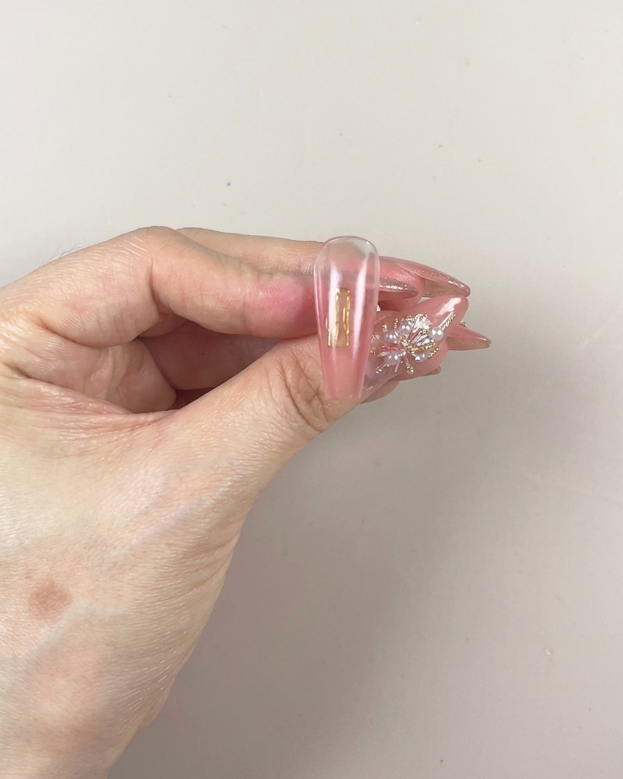Un pincel aplicando una nueva capa de gel pigmentado en la parte inferior de la uña.