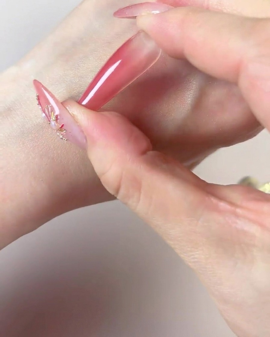 Una mano utilizando el centro oscuro de una esponja de maquillaje para añadir color concentrado en la punta de una uña larga.