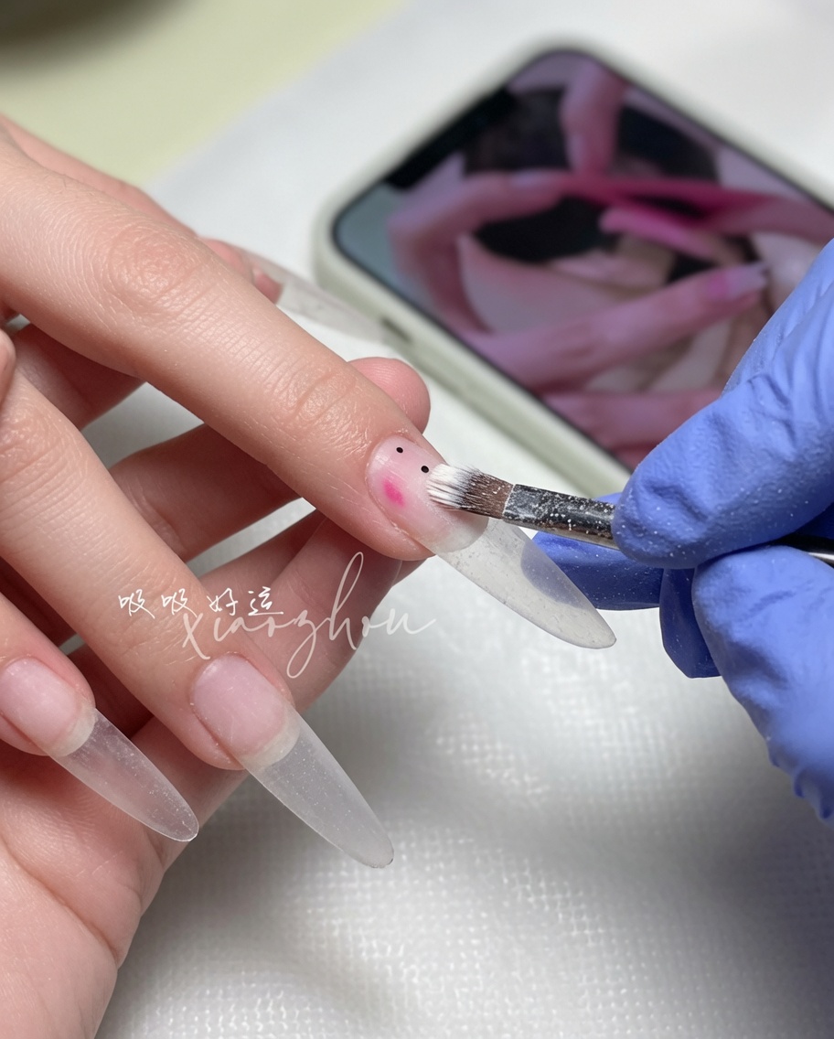 Un pincel de uñas extendiendo un esmalte de gel nude suave sobre la uña.