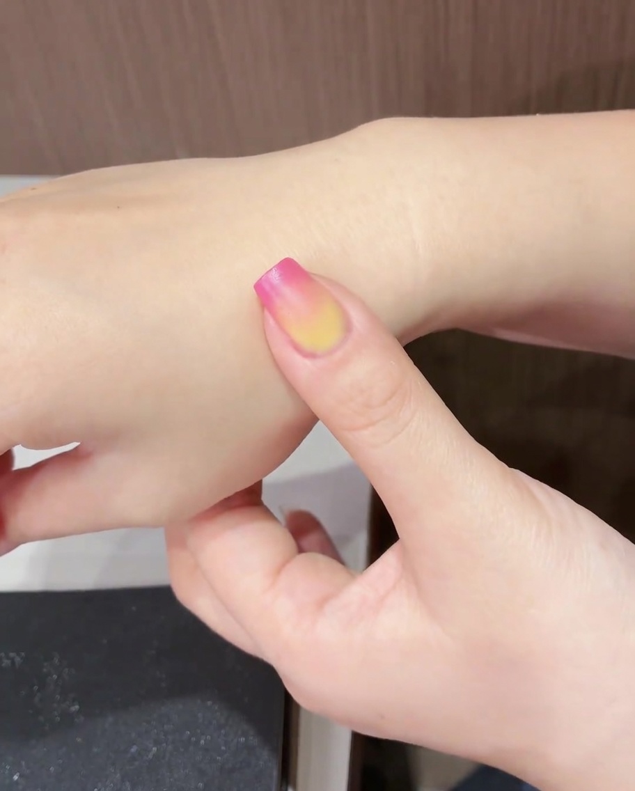 Una uña con el diseño de tulipán completado siendo curada bajo una lámpara UV/LED.