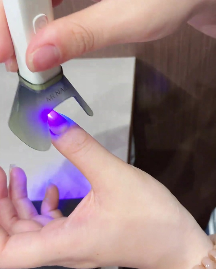 Un pincel aplicando esmalte de gel ojo de gato brillante sobre toda la superficie de una uña natural.