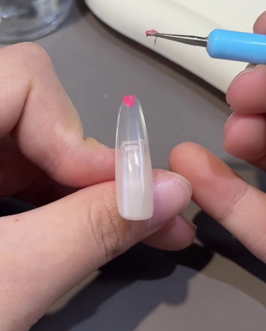 Un tip de uña siendo curado bajo una lámpara UV/LED, mostrando la superficie del gel fijada.