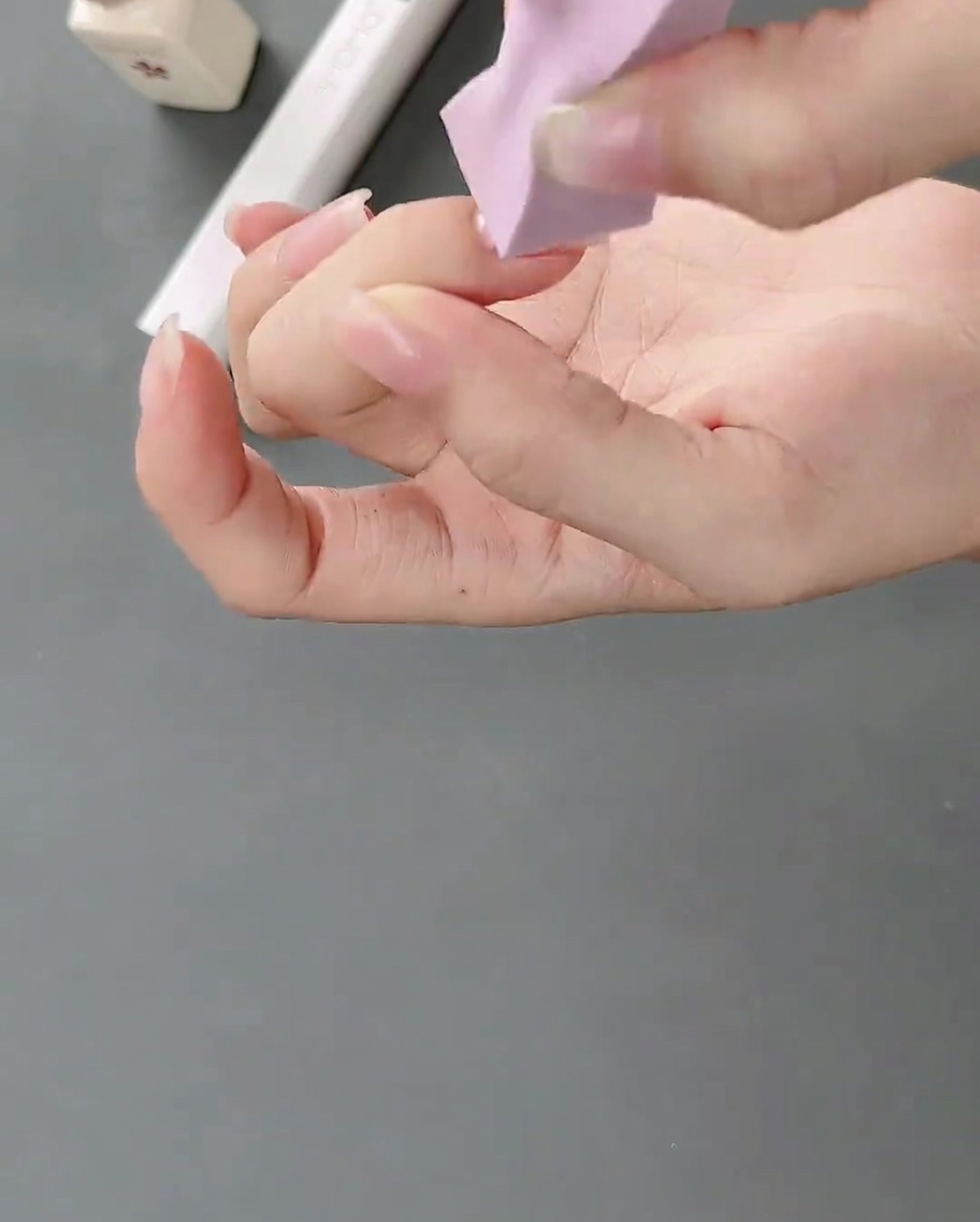 Una esponja de maquillaje aplicando gel blanco sobre una uña natural para crear un efecto de degradado suave.