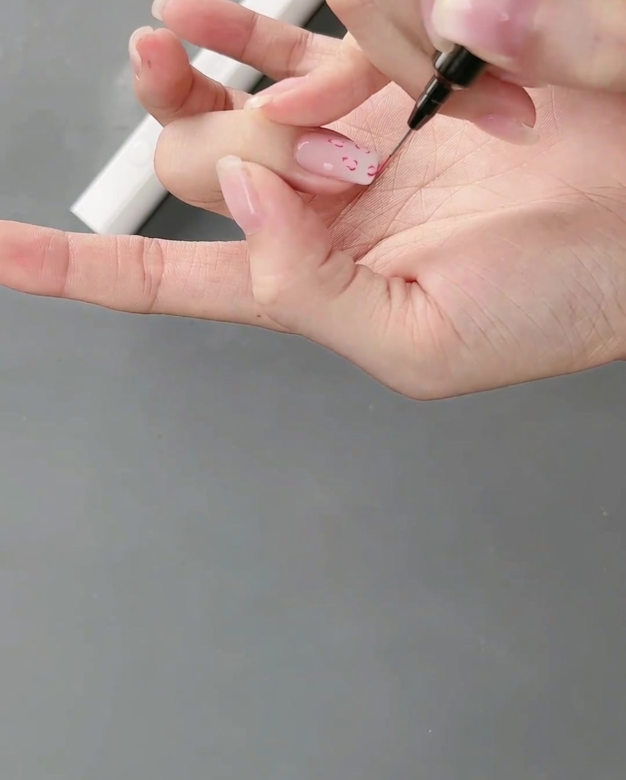 Una mano posicionada bajo una lámpara de uñas, curando el nail art de líneas finas recién pintado.