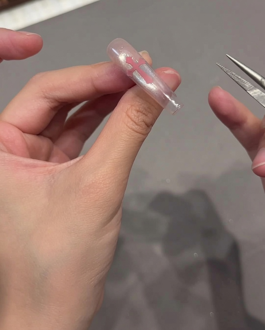 Una toallita sin pelusa siendo utilizada para limpiar la superficie de una uña terminada estilo ojo de gato.