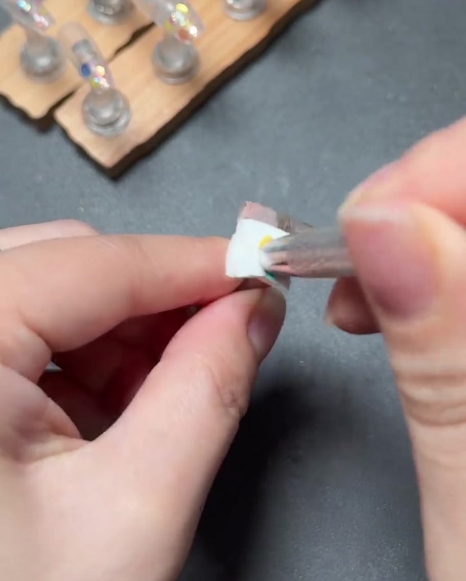 Un pincel pequeño aplicando gel rosa claro para crear un degradado suave desde la cutícula hacia abajo de la uña.