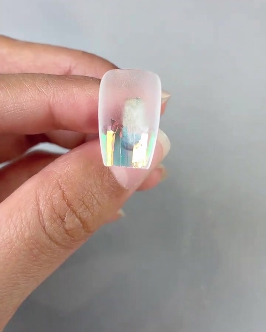 Un pincel aplicando una capa de gel finalizador transparente sobre el papel de cristal en el tip.