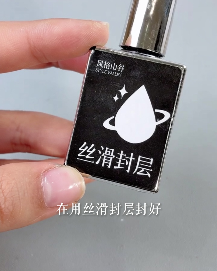 Un pincel aplicando un top coat transparente y brillante sobre un diseño de uñas terminado.