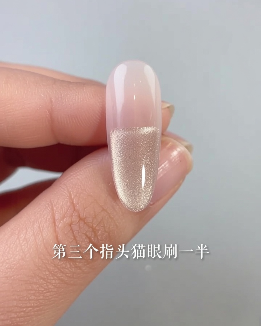 Un primer plano de una uña con un esmalte de gel ojo de gato aplicado únicamente en la mitad inferior del lecho ungueal.