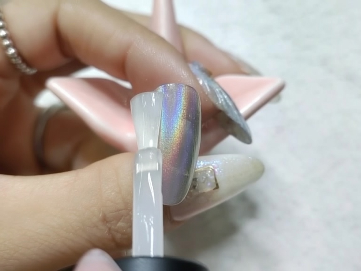 Una uña con acabado cromado curándose bajo la lámpara UV/LED tras la aplicación del top coat mate.