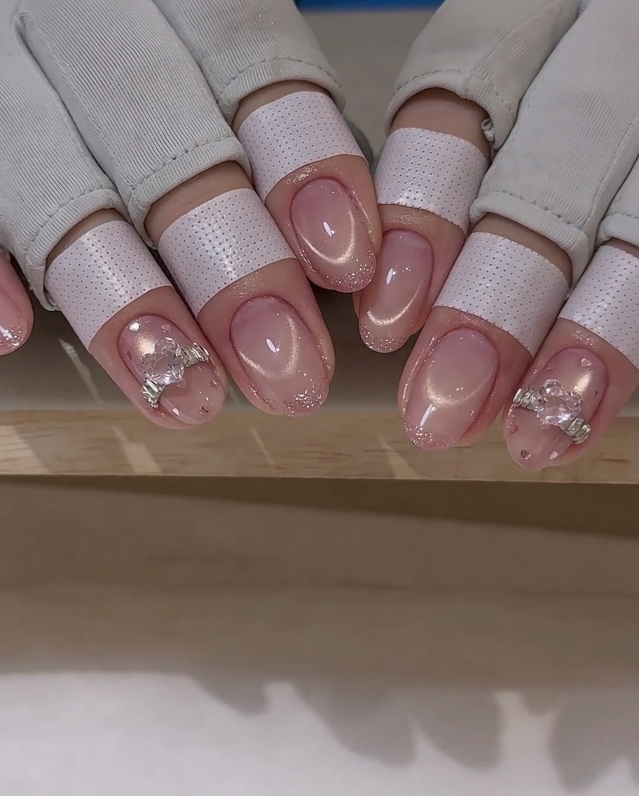 Un pincel de nail art aplicando una capa fina de top coat alrededor de un dije de cristal en una uña.