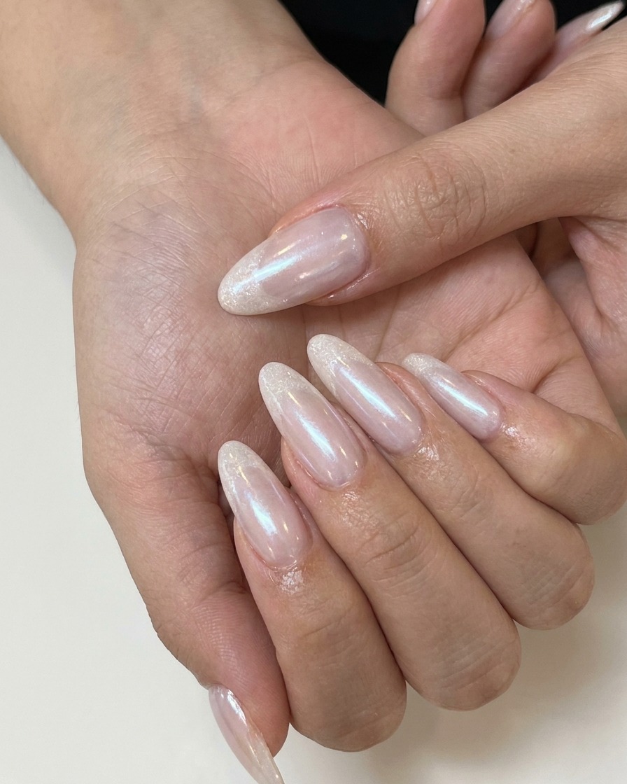 Una técnica de uñas aplicando top coat mate sobre una uña de gel nude rosada.