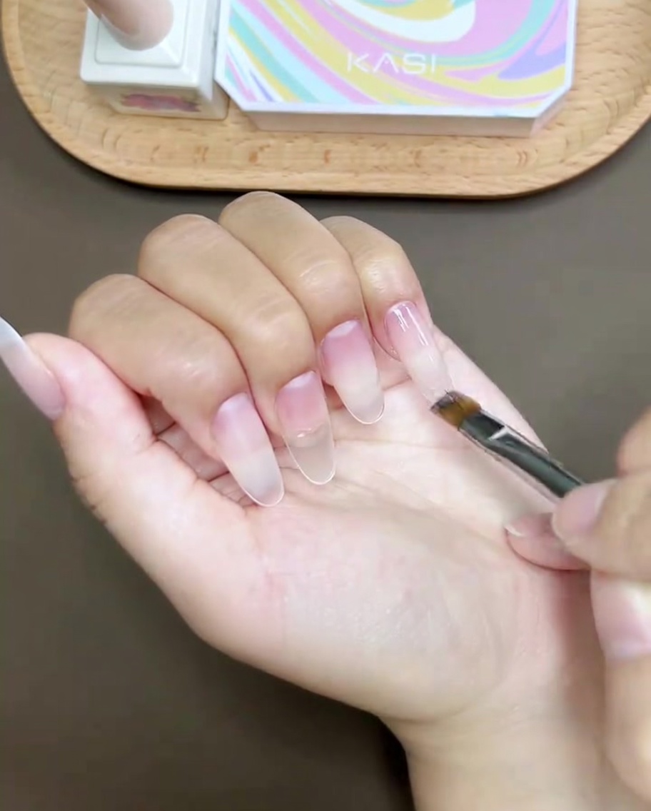 Un par de pinzas colocando un pequeño diamante de imitación sobre la superficie de la uña del pulgar.