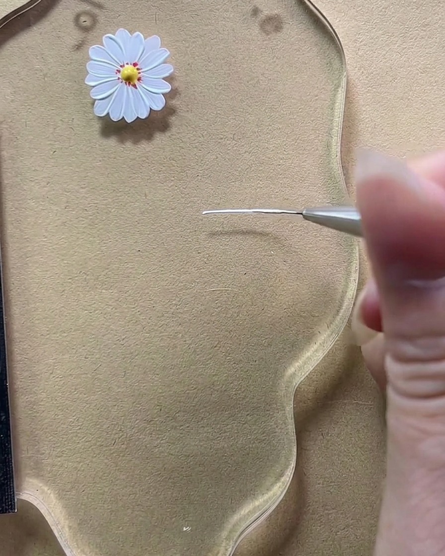 Vista de primer plano de un pincel fino dibujando una línea vertical blanca corta en una paleta transparente.