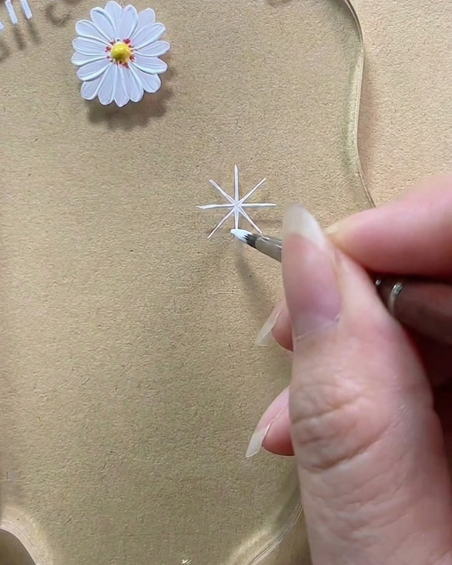 Primer plano mostrando un pincel agregando gel blanco para espesar una línea diagonal en un pétalo de lágrima redondeado.