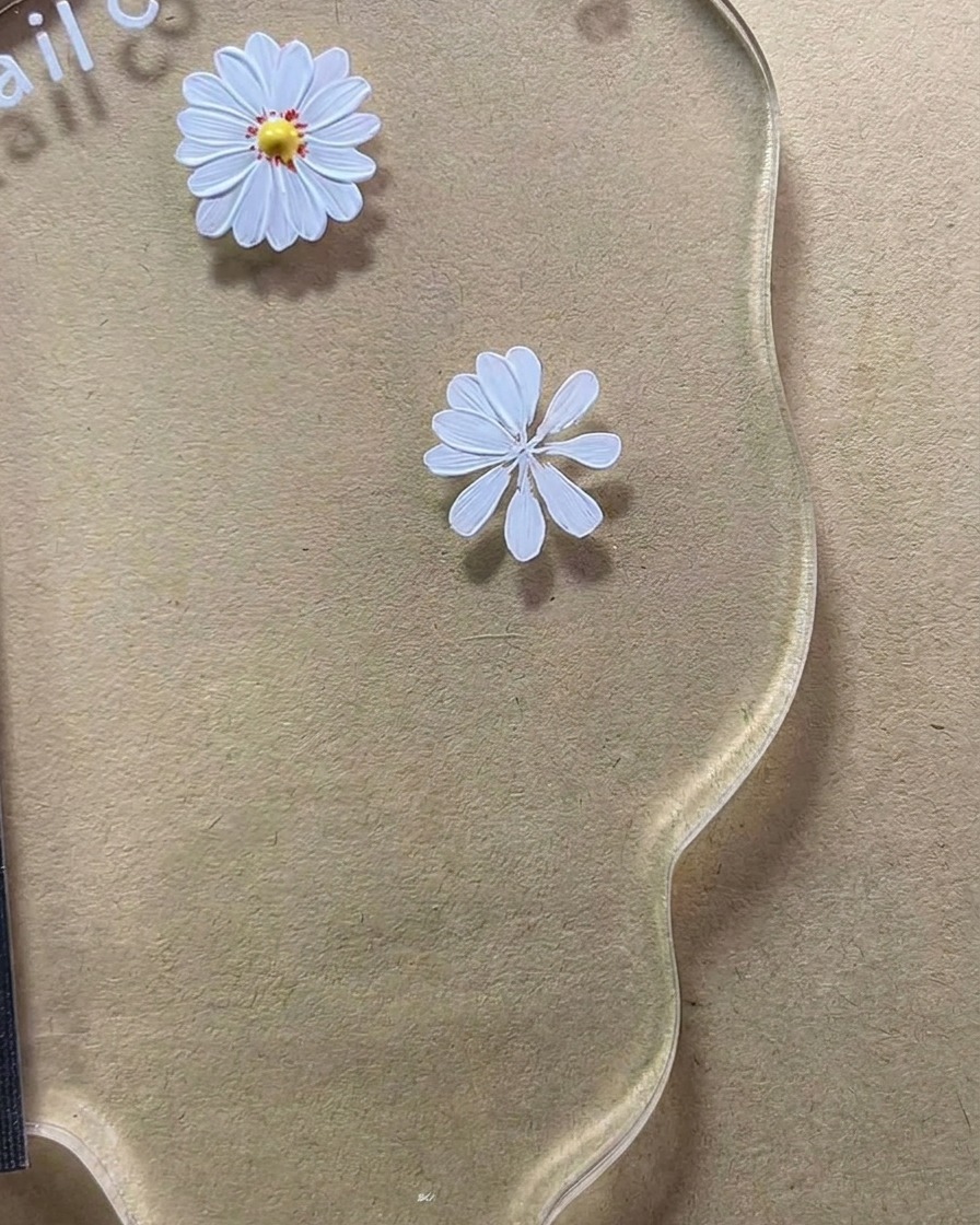 Primer plano de un diseño de margarita blanca de ocho pétalos completándose en una paleta de nail art.